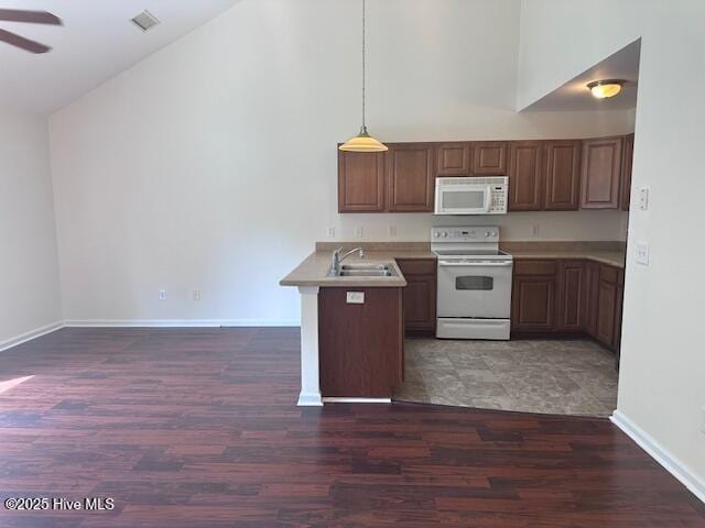 104 Lincoln Place Cir, Leland, NC 28451 - kitchen with white appliances, a peninsula, a sink, dark wood-style floors, and high vaulted ceiling