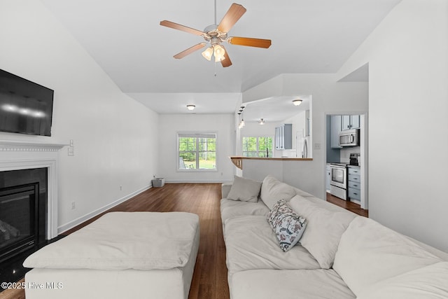 317 Inverness Dr, Hubert, NC 28539 - living room featuring vaulted ceiling, dark wood-style flooring, ceiling fan, baseboards, and a glass covered fireplace