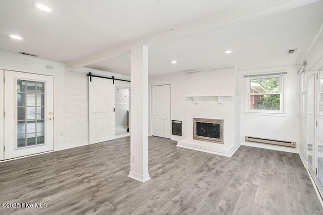 227 Rose Ave, Wilmington, NC 28403 - unfurnished living room with baseboard heating, a barn door, wood finished floors, a brick fireplace, and recessed lighting
