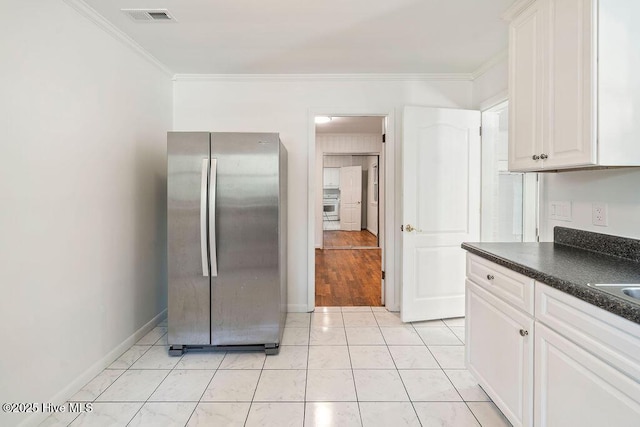 227 Rose Ave, Wilmington, NC 28403 - kitchen with freestanding refrigerator, dark countertops, crown molding, white cabinetry, and light tile patterned floors