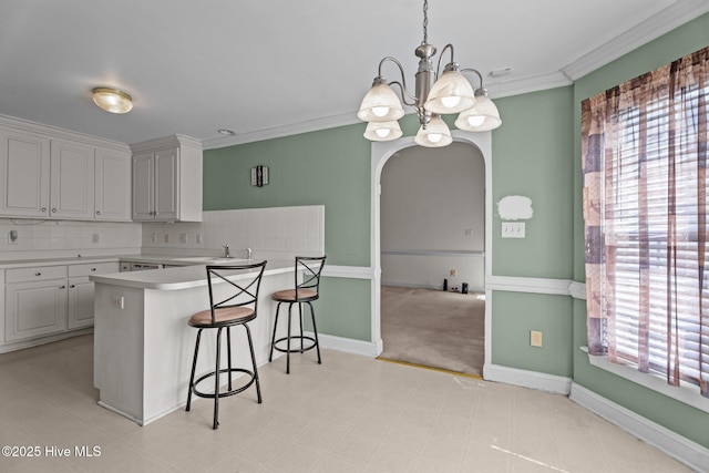 4710 Hudson Rd NW, Wilson, NC 27896 - kitchen featuring a chandelier, a kitchen breakfast bar, a peninsula, a sink, and crown molding