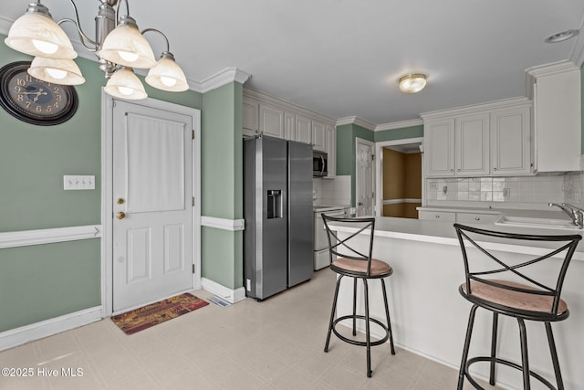 4710 Hudson Rd NW, Wilson, NC 27896 - kitchen featuring appliances with stainless steel finishes, a peninsula, a sink, decorative backsplash, and light countertops