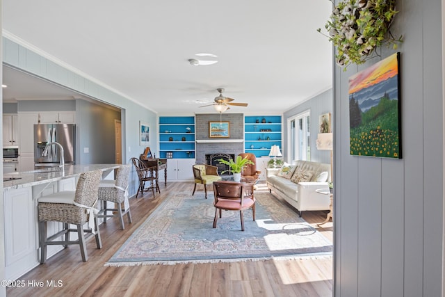 1235 Sound Shore Dr, Edenton, NC 27932 - living area featuring crown molding, ceiling fan, built in features, a fireplace, and light wood-style flooring