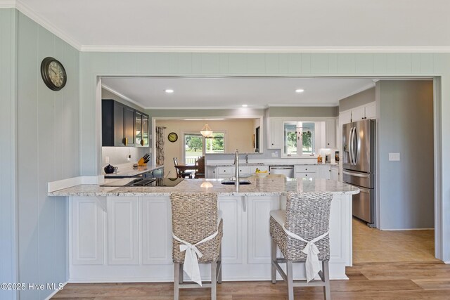 1235 Sound Shore Dr, Edenton, NC 27932 - kitchen with stainless steel appliances, a peninsula, ornamental molding, light stone counters, and a breakfast bar