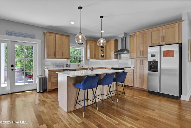 1246 Heron Run Dr, Wilmington, NC 28403 - kitchen featuring stainless steel fridge with ice dispenser, wall chimney range hood, light wood-type flooring, light countertops, and recessed lighting