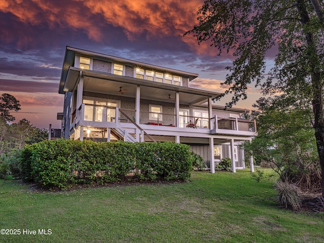 1246 Heron Run Dr, Wilmington, NC 28403 - back of house at dusk featuring a yard, stairway, a balcony, and a ceiling fan