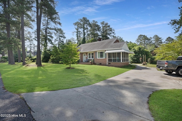 1206 Lancaster Ln, Rockingham, NC 28379 - view of front of property featuring a sunroom, driveway, brick siding, a front yard, and a chimney