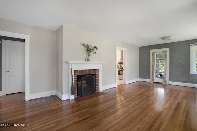 1206 Lancaster Ln, Rockingham, NC 28379 - unfurnished living room with wood finished floors, a brick fireplace, and baseboards
