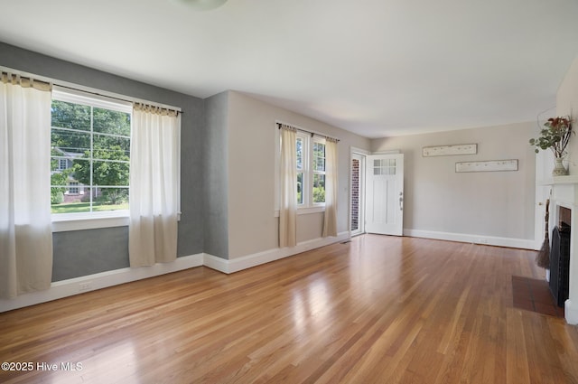1206 Lancaster Ln, Rockingham, NC 28379 - unfurnished living room with light wood-type flooring, a fireplace with flush hearth, and baseboards