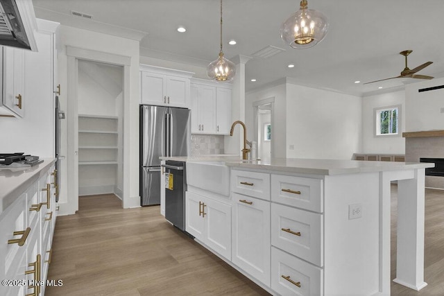324 Grayhawk Cir, Wilmington, NC 28411 - kitchen with stainless steel appliances, light countertops, white cabinetry, ceiling fan, and light wood-type flooring