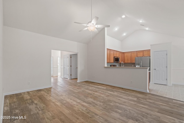 94 Field Planters Cir, Calabash, NC 28467 - unfurnished living room featuring high vaulted ceiling, a ceiling fan, light wood finished floors, baseboards, and a sink