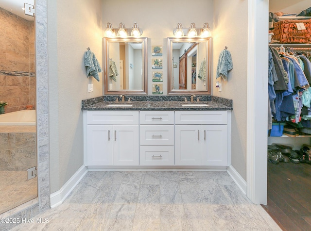 104 Soundside Estates Dr, Grandy, NC 27939 - bathroom featuring double vanity, a walk in closet, baseboards, and tiled shower