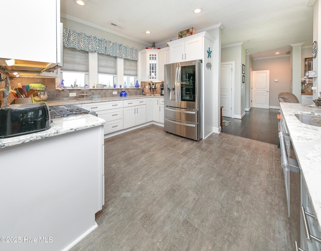 104 Soundside Estates Dr, Grandy, NC 27939 - kitchen with stainless steel refrigerator with ice dispenser, ornamental molding, recessed lighting, white cabinets, and light stone counters