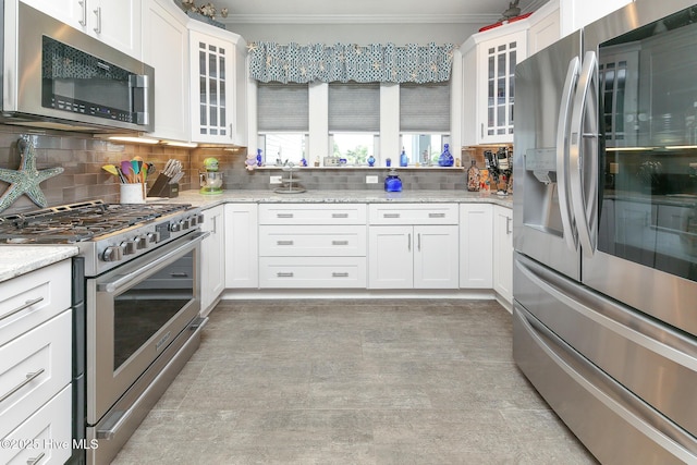 104 Soundside Estates Dr, Grandy, NC 27939 - kitchen with appliances with stainless steel finishes, crown molding, white cabinets, decorative backsplash, and glass insert cabinets