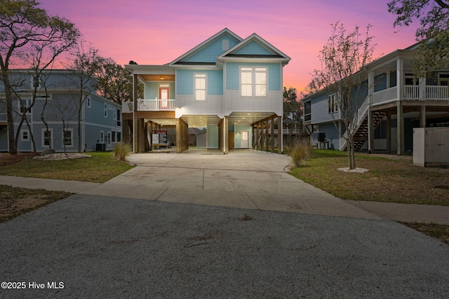 2705 E Oak Island Dr, Oak Island, NC 28465 - coastal inspired home with a carport, a front lawn, driveway, and stairway