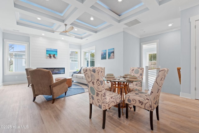 2705 E Oak Island Dr, Oak Island, NC 28465 - dining area featuring light wood finished floors, a ceiling fan, coffered ceiling, a glass covered fireplace, and beamed ceiling