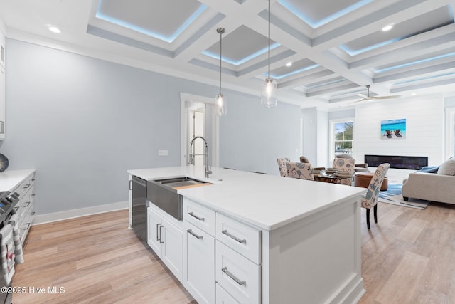 2705 E Oak Island Dr, Oak Island, NC 28465 - kitchen with a sink, coffered ceiling, light wood finished floors, a glass covered fireplace, and white cabinets
