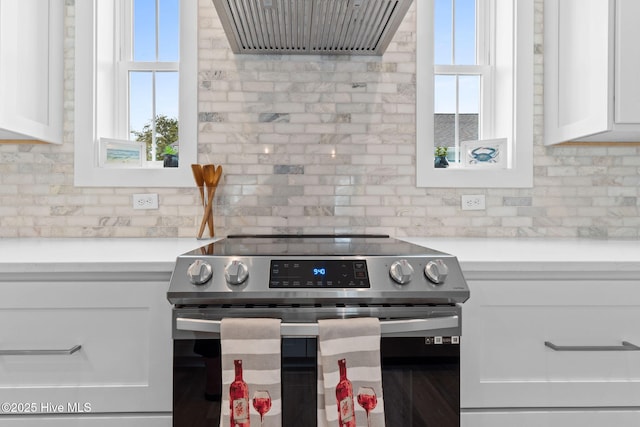 2705 E Oak Island Dr, Oak Island, NC 28465 - kitchen featuring stainless steel electric range oven, ventilation hood, white cabinets, and light countertops