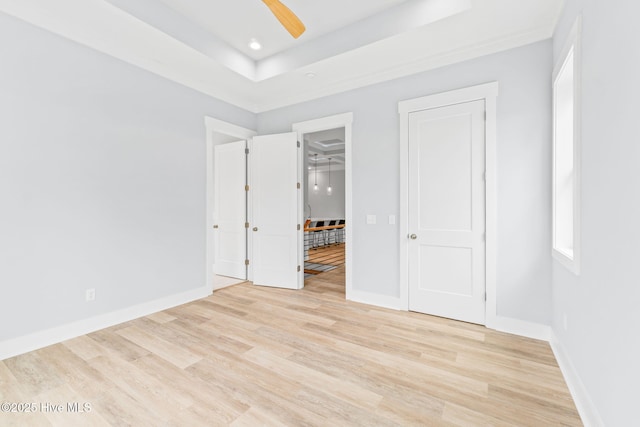 2705 E Oak Island Dr, Oak Island, NC 28465 - unfurnished bedroom with light wood finished floors, baseboards, recessed lighting, a tray ceiling, and multiple windows