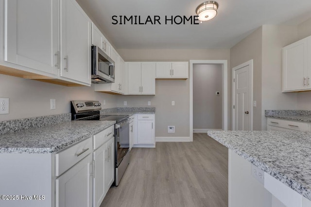 98 NE Dr NW, Calabash, NC 28467 - kitchen featuring stainless steel appliances, light wood finished floors, white cabinets, light stone counters, and baseboards
