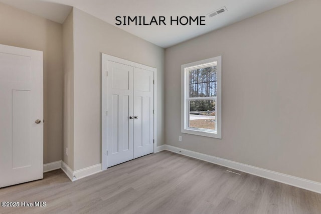 98 NE Dr NW, Calabash, NC 28467 - unfurnished bedroom featuring light wood finished floors, baseboards, and a closet