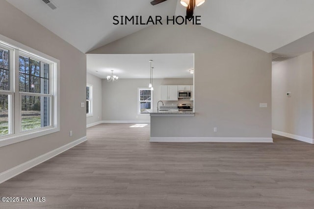 98 NE Dr NW, Calabash, NC 28467 - unfurnished living room with a sink, lofted ceiling, a chandelier, ceiling fan, and wood finished floors