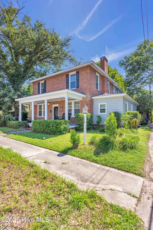 114 N 16th St, Wilmington, NC 28401 - view of front facade featuring a chimney, a front lawn, brick siding, and covered porch