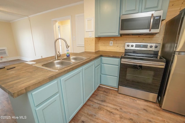 2264 New River Inlet Rd Unit 210, North Topsail Beach, NC 28460 - kitchen featuring stainless steel appliances, a sink, crown molding, a peninsula, and light wood-style flooring