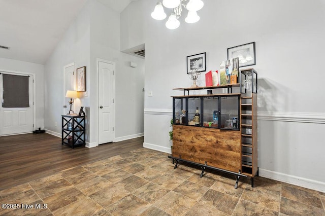 213 Lockwood Ct, Hubert, NC 28539 - bar area featuring a chandelier, baseboards, stone finish floors, and high vaulted ceiling