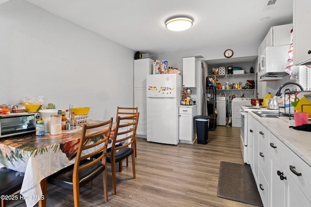 406 Walnut St, Elizabeth City, NC 27909 - kitchen featuring washer and dryer, freestanding refrigerator, a sink, light wood-style flooring, and white cabinetry