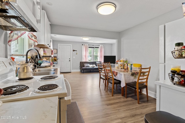 406 Walnut St, Elizabeth City, NC 27909 - kitchen with white electric range oven, range hood, light wood-type flooring, light countertops, and white cabinetry