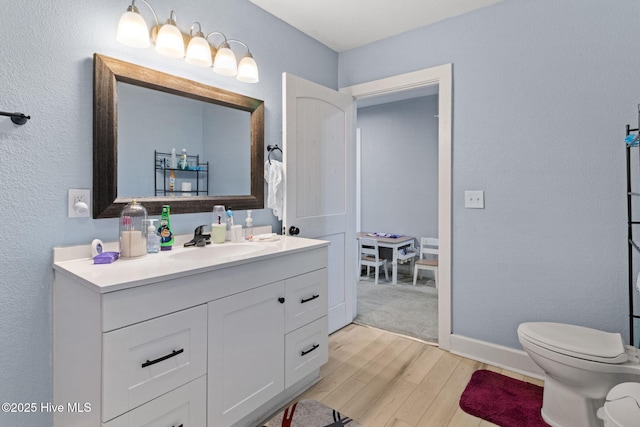 406 Walnut St, Elizabeth City, NC 27909 - bathroom featuring wood finished floors, vanity, toilet, baseboards, and a textured wall
