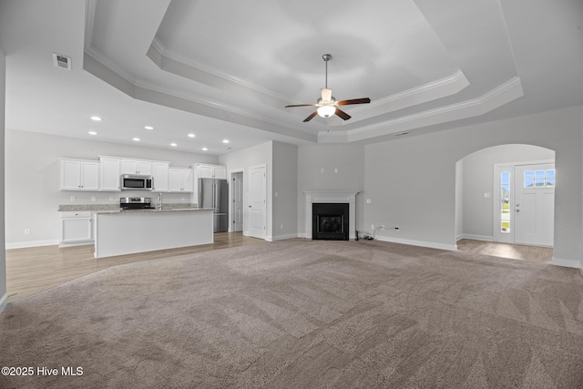2001 Snapper St, New Bern, NC 28562 - unfurnished living room featuring a tray ceiling, crown molding, a ceiling fan, baseboards, and recessed lighting