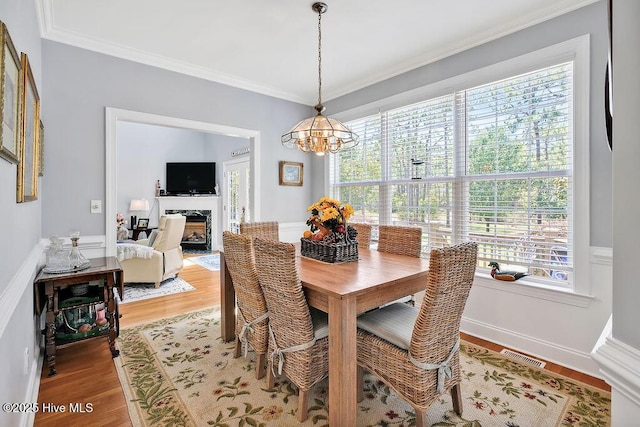 3212 Wexford Way, Southport, NC 28461 - dining room with a chandelier, ornamental molding, light wood-style floors, and a fireplace