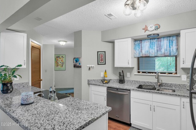 728 Azalea Dr Unit 426, Hampstead, NC 28443 - kitchen with stainless steel dishwasher, a sink, white cabinets, light stone counters, and a peninsula