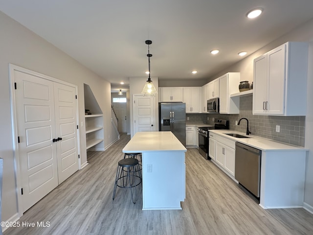 8288 Paramount Pt, Winnabow, NC 28479 - kitchen with stainless steel appliances, a sink, a breakfast bar area, light wood finished floors, and white cabinets