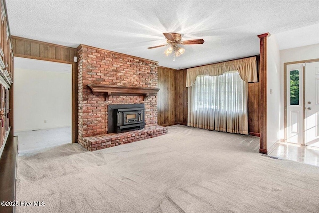 102 Trollingwood Dr, Goldsboro, NC 27534 - unfurnished living room featuring wooden walls, carpet, a wood stove, a ceiling fan, and a textured ceiling