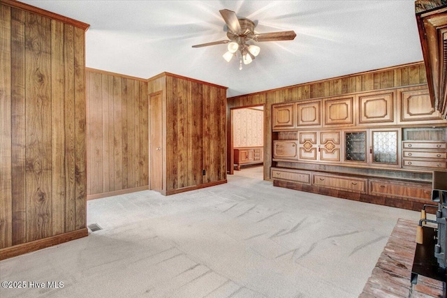 102 Trollingwood Dr, Goldsboro, NC 27534 - unfurnished living room with wooden walls, a ceiling fan, light carpet, baseboards, and ornamental molding