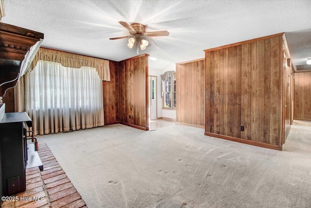 102 Trollingwood Dr, Goldsboro, NC 27534 - unfurnished living room with a wood stove, wooden walls, ceiling fan, carpet, and a textured ceiling