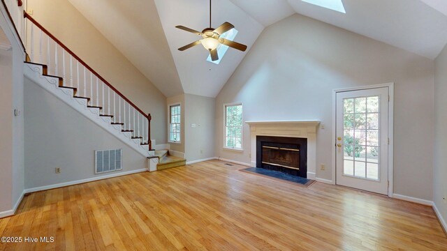165 Sandhurst Pl, Southern Pines, NC 28387 - unfurnished living room featuring wood finished floors, stairway, a ceiling fan, a glass covered fireplace, and a skylight