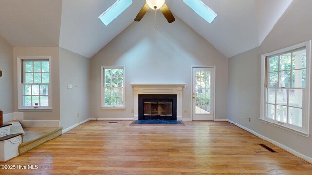 165 Sandhurst Pl, Southern Pines, NC 28387 - unfurnished living room featuring a skylight, a fireplace with flush hearth, light wood-style flooring, and high vaulted ceiling