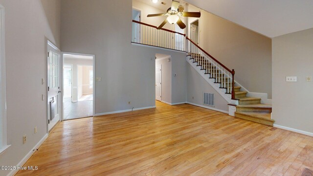 165 Sandhurst Pl, Southern Pines, NC 28387 - unfurnished living room with ceiling fan, wood finished floors, a towering ceiling, stairway, and baseboards