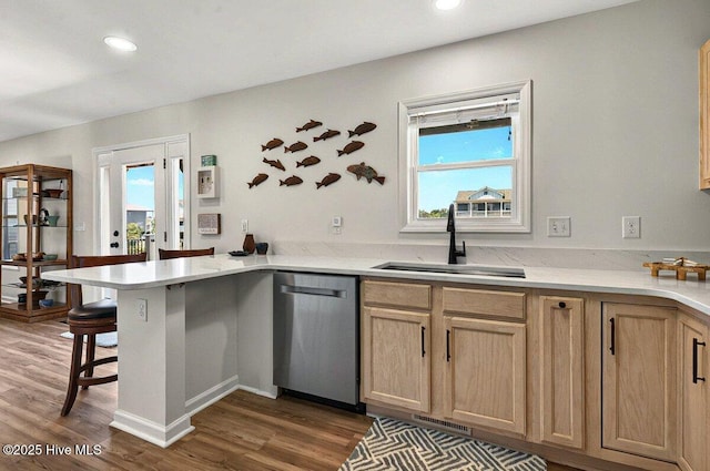 1116 E Beach Dr, Oak Island, NC 28465 - kitchen featuring stainless steel dishwasher, a sink, a peninsula, wood finished floors, and plenty of natural light
