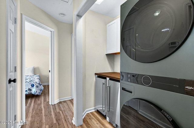 1116 E Beach Dr, Oak Island, NC 28465 - laundry room with stacked washer / dryer, cabinet space, light wood-style floors, and baseboards