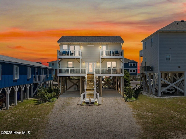1116 E Beach Dr, Oak Island, NC 28465 - view of front of home featuring a carport, stairway, a balcony, and driveway