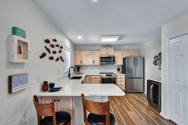 1116 E Beach Dr, Oak Island, NC 28465 - kitchen featuring stainless steel appliances, beverage cooler, light brown cabinets, a sink, and a peninsula