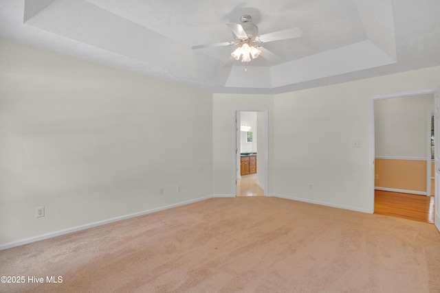 109 Country Club Dr, Rockingham, NC 28379 - empty room featuring a tray ceiling, ceiling fan, light colored carpet, and baseboards