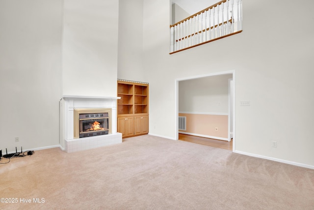 109 Country Club Dr, Rockingham, NC 28379 - unfurnished living room with carpet flooring, a towering ceiling, a glass covered fireplace, and baseboards
