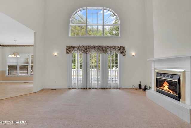 109 Country Club Dr, Rockingham, NC 28379 - unfurnished living room with a high ceiling, a chandelier, a glass covered fireplace, carpet flooring, and baseboards