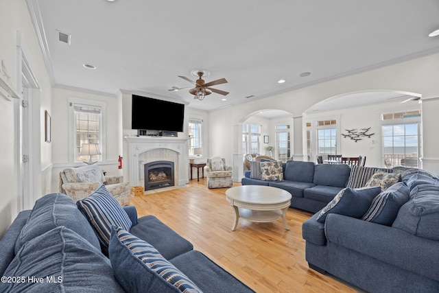 4248 Island Dr, North Topsail Beach, NC 28460 - living area with arched walkways, ceiling fan, crown molding, light wood-style flooring, and a fireplace with flush hearth